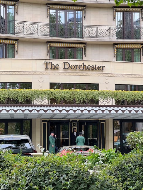 A wide view of a multi-storey white residential building with classical architectural details, including decorative elements around the windows and a series of balconies with black wrought iron railin